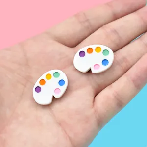 Close-up view of two colorful miniature paint palette resin charms for DIY craft projects