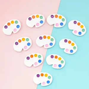 Detailed view of miniature white resin paint palette charms for DIY crafts and decor.