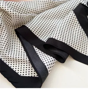 Detail of black and white polka dot silk scarf, elegant fashion accessory for women and girls.
