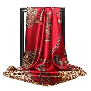 Detail view of a red satin silk scarf featuring luxury baroque chain and leopard print.