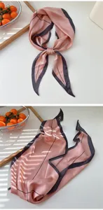 Close-up detail of the elegant pink and dark grey silk ribbon scarf, showcasing its unique pattern.