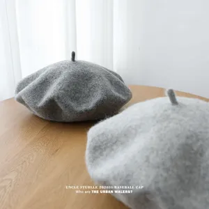 Vista detallada de boina de lana gris sobre mesa de madera, luz suave, accesorio de invierno chic.