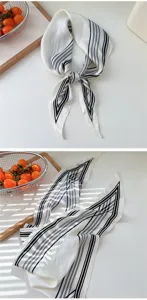 Silk scarf detail view, elegant black and white striped diamond design for versatile wear.