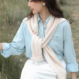 Detailansicht beige Strick-Schulterüberwurf, stylisches Crossover-Design über Jeanshemd, Outdoor.