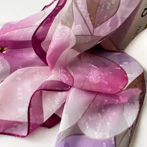 Close-up detail of a lightweight purple patterned silk scarf with elegant floral jacquard.
