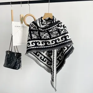 Detailed view of black and white jacquard shawl, tassel hem and vintage pattern design showcase.