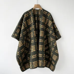 Vista detallada de un poncho de punto verde oscuro con un elegante diseño de lunares.