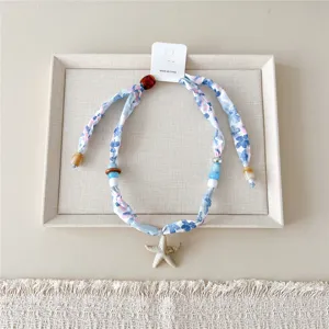 Bloemige stoffen sjaal ketting met zeester hanger, elegant zomerse strand sieraden accessoire.