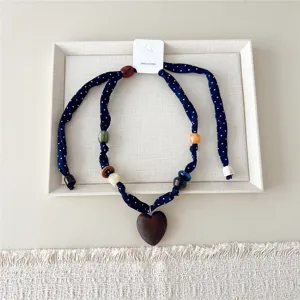 Donkerblauwe polkadot stoffen sjaalketting met kleurrijke kralen en een houten hartvormige hanger.