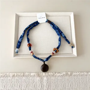 Close-up detail van de elegante blauwe zijden sjaalketting versierd met prachtige houten kralen.