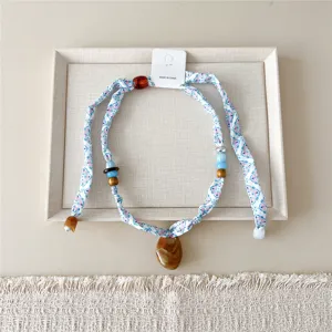 Gedetailleerd shot van een chique smalle geprinte zijden sjaalketting met hars hanger.