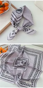 Detail shot of the light purple cotton square scarf featuring classic paisley print patterns and a cute label tag.