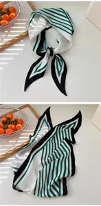 Green and white striped silk scarf detail view, elegant black border, versatile accessory.