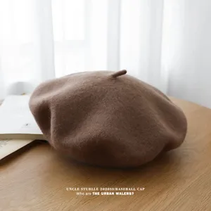 Vista detallada de la clásica boina de lana marrón con textura suave sobre mesa de madera.
