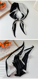Close-up detail of black and white striped silk scarf, elegant hair ribbon and neck accessory.