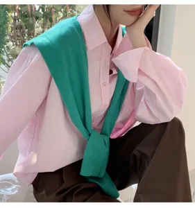 Details of women solid color knit shawl draped over pink shirt fashion styling outfit.