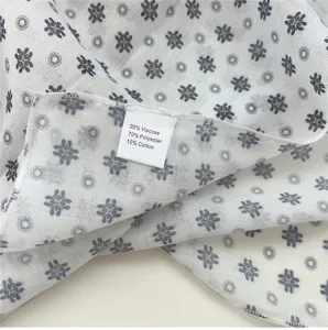Fabric detail view of women's floral square scarf showing soft texture and label.