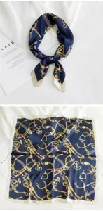 Detalle de pañuelo de seda azul marino clásico con elegante diseño de estribo y cadenas doradas.
