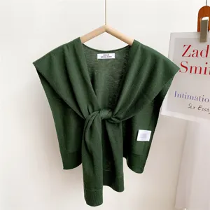 Detailed view of the dark green knitted shawl, showing fine texture and front knot design.