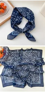 Detailed view of the dark blue paisley square scarf showing intricate floral patterns and borders.