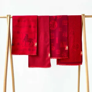 Detail view of Chinese New Year red scarves featuring festive horse and blessing patterns.