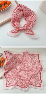 Delicate pink floral square scarf detail showing soft fabric texture and elegant red border design.