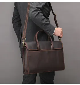 Detail view of the brown leather business briefcase with handle and shoulder strap for men.