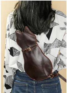 Detail view of a dark brown genuine leather cat-shaped shoulder bag worn on back.