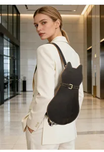 Detailed view of the cute cat-shaped leather backpack worn by a model in a modern lobby.