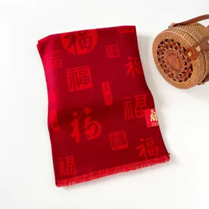 Detailed view of the red festive scarf featuring traditional Chinese blessing patterns and tag.