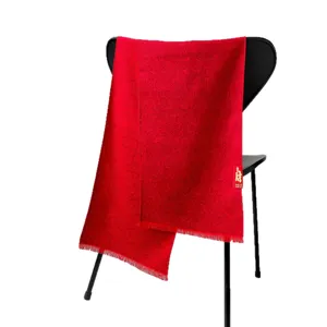 Red New Year scarf with fringe traditional pattern draped over chair for holiday gift and party wear.