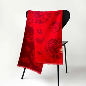 Detail shot of a festive red scarf featuring traditional dragon and coin patterns draped on a chair.