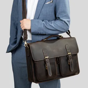 Detail view of vintage leather messenger bag with dual buckle pockets and sturdy handle.