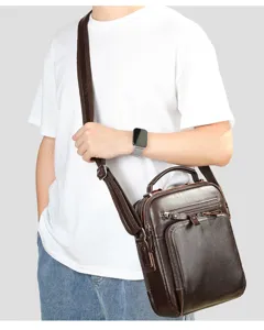 Detail view of the brown leather men messenger bag worn across body, showing zipper pockets.
