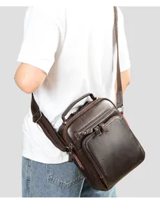 Close-up detail of the brown leather shoulder bag showing multi-zipper pockets and strap.