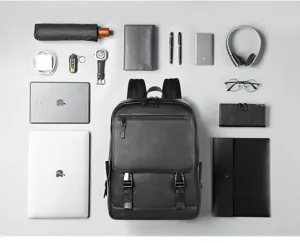 Vue détaillée du sac à dos d'affaires en cuir noir avec agencement soigné des accessoires.