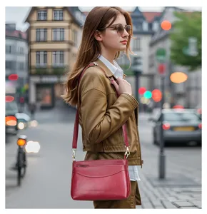 Detailed view of the red leather shoulder bag in a street lifestyle setting, practical design.