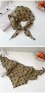 Vue de détail rapprochée du foulard triangulaire à pois kaki avec bordure noire.