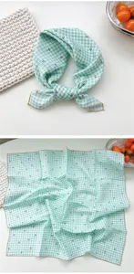 Detail view of the green checkered cotton scarf showing cherry print, texture and fine edges.