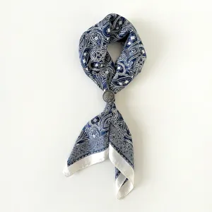 Dettaglio ravvicinato di foulard quadrato in raso paisley blu con elegante fibbia vintage.