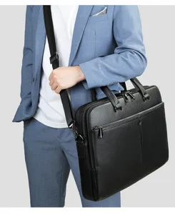 Primo piano di borsa ventiquattrore in vera pelle nera da uomo con zip e tracolla.