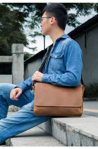 Detail view of the vintage brown crazy horse leather messenger bag worn outdoors, showing texture.