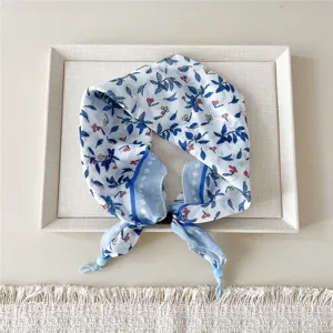 Detailed close-up of blue and white floral neck scarf with delicate botanical print and beads.