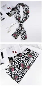 Detail shot of a chic leopard print skinny silk scarf with floral accent, styled flat lay.