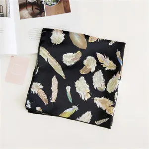 Close-up detail of a black silk square scarf featuring elegant colorful feather pattern prints.