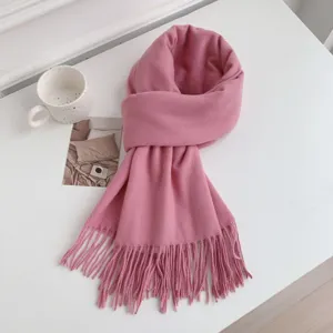 Close-up of pink imitation cashmere tassel scarf, cozy winter accessory on white surface.