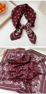 Detailed close-up shot of a dark red square silk scarf featuring classic paisley and star print.