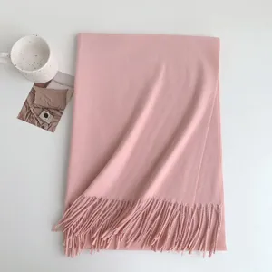 Pink winter tassel scarf detail flat lay, soft imitation cashmere fabric texture close-up.