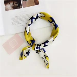 Detail shot of a stylish yellow and blue silk square scarf with chic floral print patterns.