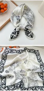 Silk scarf close-up, black and white floral butterfly pattern detail, elegant design.
